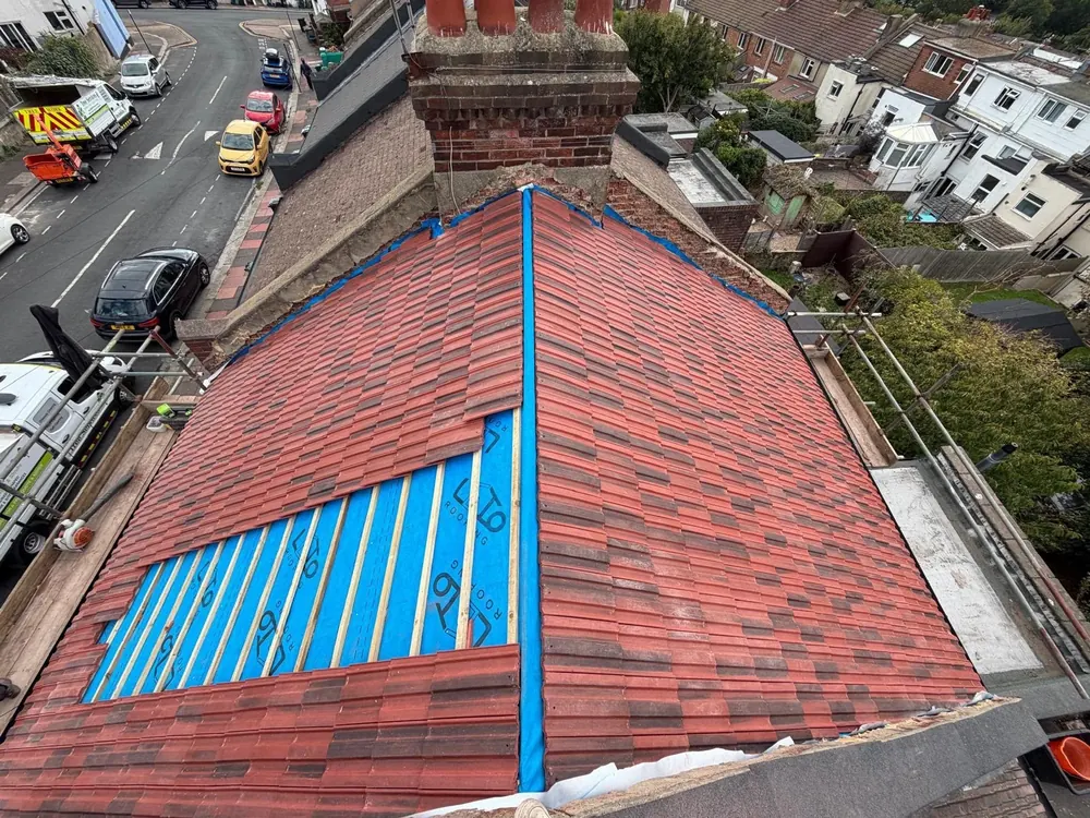 Red tiled roof part re-covered with new membrane and battens showing