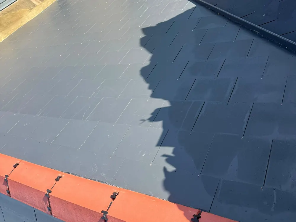 New slate roof slope with a red clay ridge