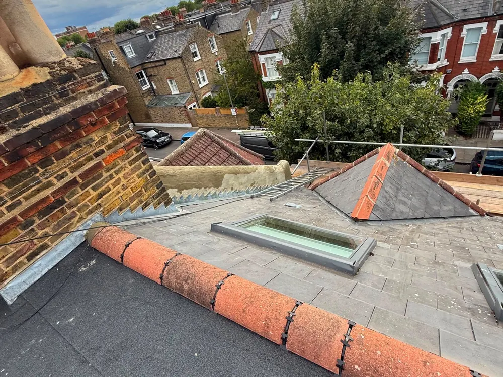 Finished flat roof meeting a red clay ridge with a roof window behind