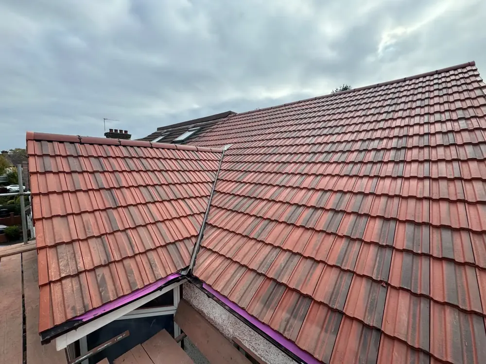 Finished red tiled roof with a dormer and a valley