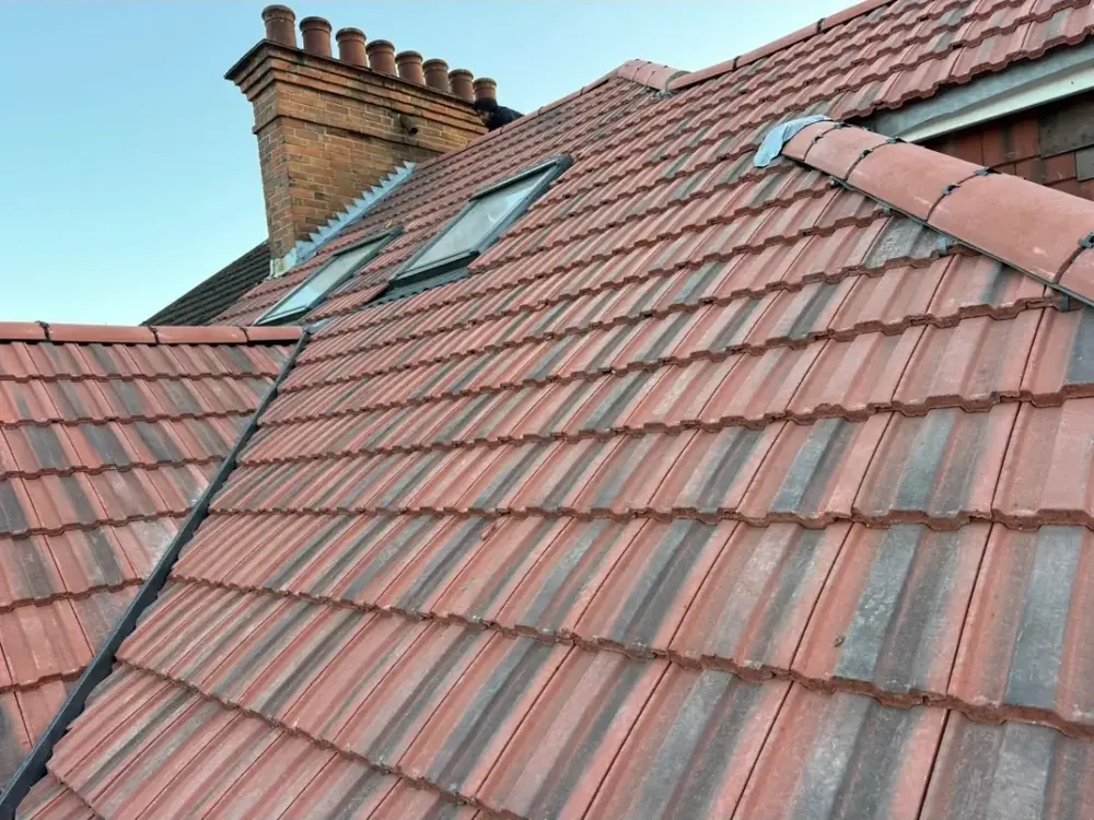 Red tiled roof with roof windows and a brick chimney stack with pots