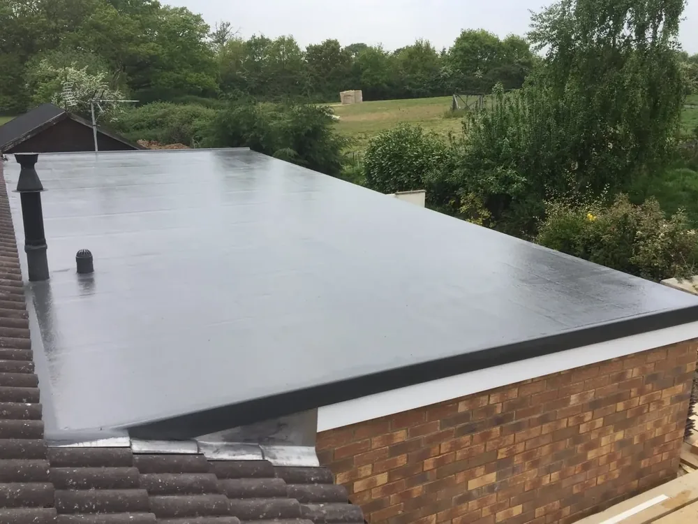 Finished grey flat roof on a brick extension beside a garden