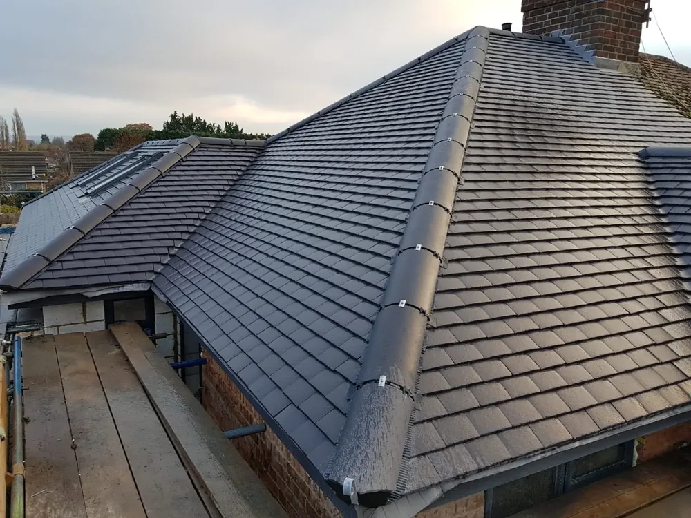 Grey tiled hip roof re-laid with a new ridge, scaffold below