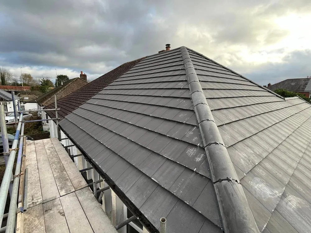 New grey tiled hipped roof seen from the scaffold