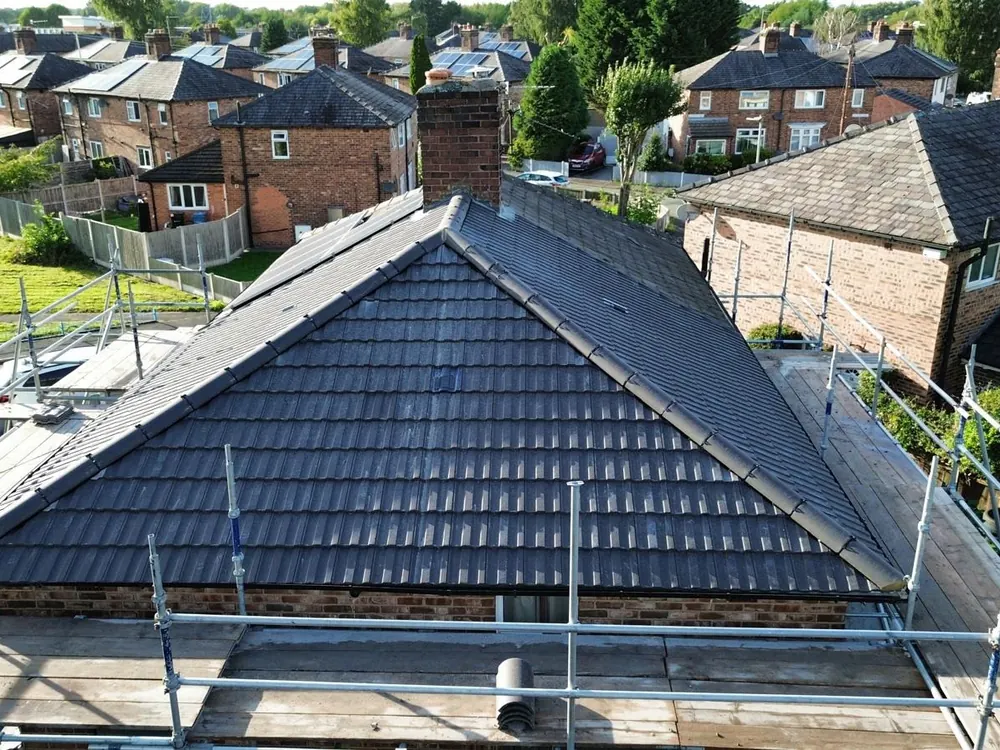 Finished grey tile hip roof seen from height over a north Manchester street
